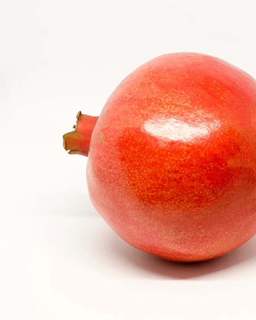 A deep red pomegranate, skin taut and unblemished